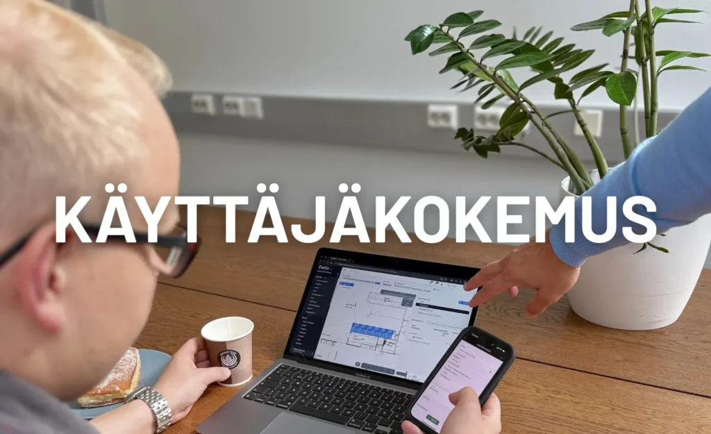 Kaksi henkilöä tarkastelee Evelian toiminnanohjausjärjestelmää läppärillä ja puhelimella. Toinen osoittaa näytöllä olevaa projektinäkymää, mikä korostaa ohjelmiston selkeää käyttäjäkokemusta.